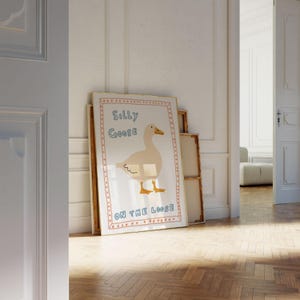 Peut inclure: Une illustration encadr&eacute;e d'une oie blanche avec le texte "Silly Goose On The Loose" dans un style dessin&eacute; &agrave; la main color&eacute;.