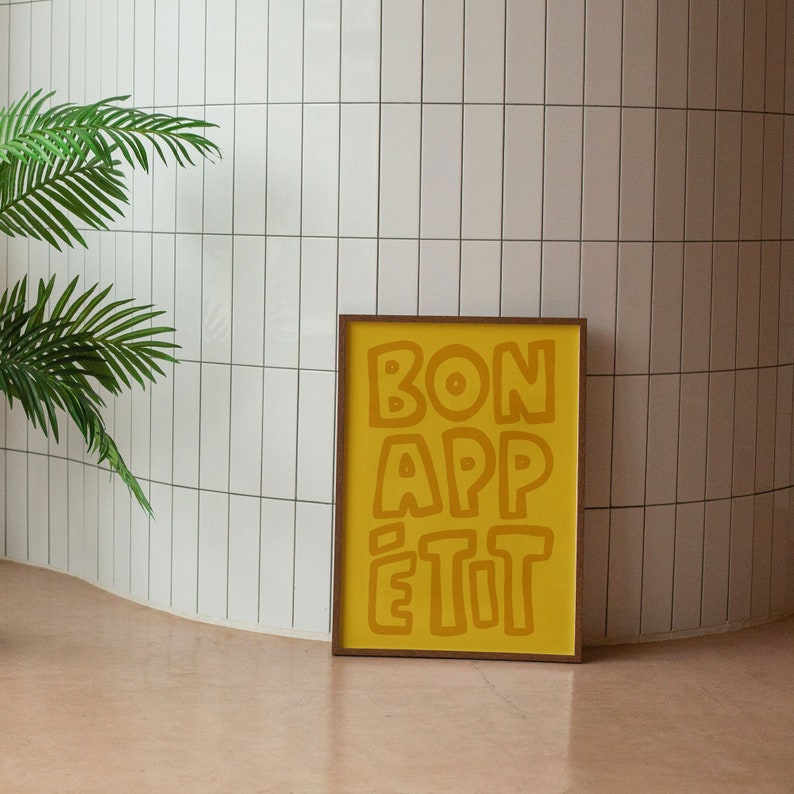 May include: A framed print with a yellow background and the text "BON APP&Eacute;TIT" in a bold, stylized font.