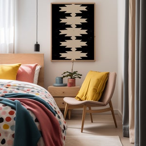 May include: A bedroom with a bed, a chair, a nightstand, and a framed print with a geometric pattern. The bed has a white and colorful polka dot duvet cover, a teal blanket, and a pink throw blanket. The chair is upholstered in beige fabric and has a yellow pillow. The nightstand is made of wood and has a small plant on top. The print is black and white and has a geometric pattern.