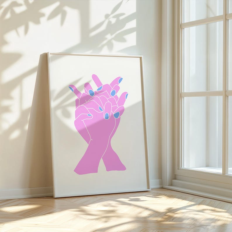 May include: A white framed print with a pink line drawing of two hands with blue nail polish. The hands are intertwined and overlapping.
