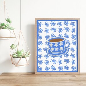 May include: A framed print of a blue and white teacup with a floral pattern on a white background with a blue floral pattern.