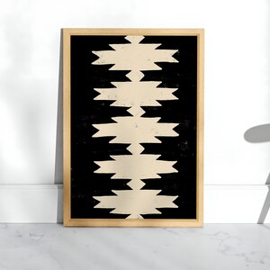 May include: A framed print with a geometric pattern in black and beige. The pattern is made up of repeating shapes that resemble arrows or zigzags.