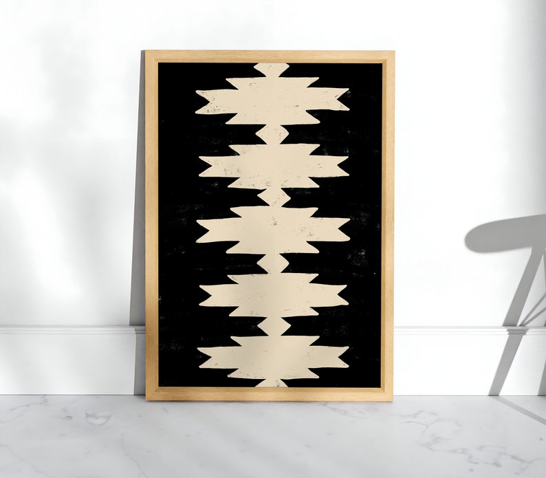 May include: A framed print with a geometric pattern in black and beige. The pattern is made up of repeating shapes that resemble arrows or zigzags.