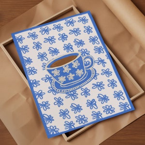 May include: A white teacup with a blue floral pattern and brown liquid inside, sitting on a white saucer with a blue floral pattern. The teacup and saucer are on a white background with a blue floral pattern.