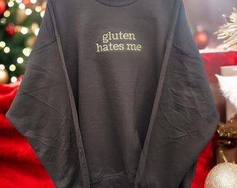 Sudadera bordada con texto "Gluten Hates Me" y cuello redondo.
