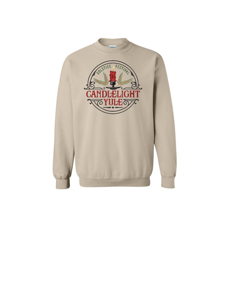 May include: A tan sweatshirt with a circular logo on the front. The logo is black and white with a red candle and the text 'Solstice Festival Candlelight Yule'.