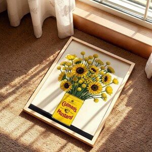 May include: A framed print featuring a bouquet of bright yellow sunflowers and billy buttons arranged in a yellow Colman's Mustard tin. The artwork displays the text Colman's Mustard on the front of the tin, set against a light cream background.