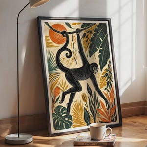 May include: A framed wall art print featuring a black spider monkey hanging from a branch, surrounded by stylized tropical foliage in shades of orange, yellow, and dark green, set against a cream-colored background with a circular orange sun.