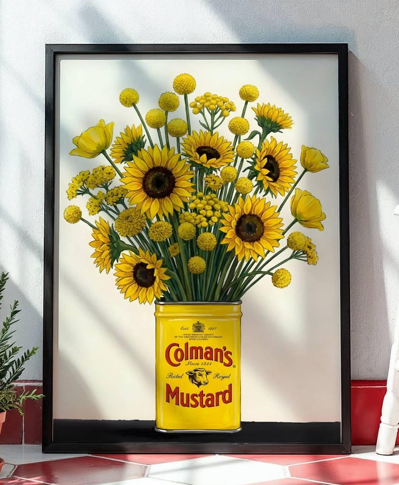May include: A framed print featuring a bouquet of bright yellow sunflowers and billy ball flowers arranged in a vintage yellow Colman's Mustard tin. The tin displays the red Colman's logo, a bull's head emblem, and the text Mustard, Estd 1814.