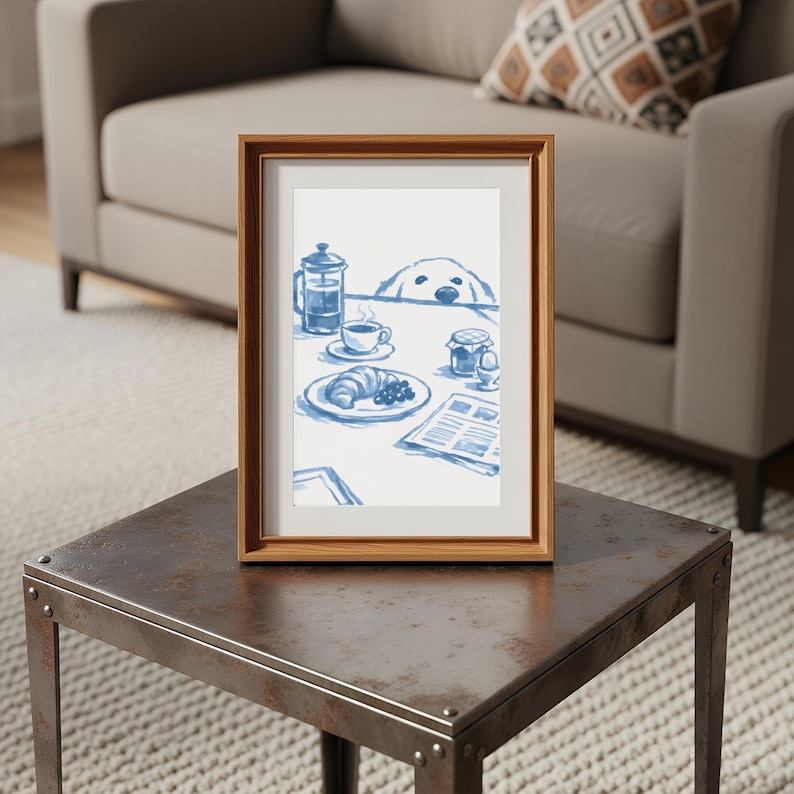May include: A framed art print featuring a blue and white illustration of a breakfast table with a French press, a coffee cup, a croissant, a jar, an egg, and a newspaper, with a dog peeking over the edge of the table at the food items.