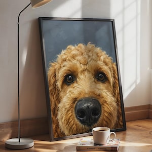 Könnte beinhalten: Ein gerahmter vertikaler Wandkunstdruck mit einem Nahporträt eines goldbraunen, lockigen Hundes mit großen dunklen Augen und einer markanten schwarzen Nase vor einem dunkelgrauen Hintergrund in einem schmalen schwarzen Rahmen.
