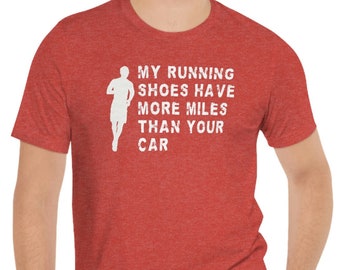 May include: Red heather t-shirt with white text that reads "My running shoes have more miles than your car". A white silhouette of a runner is to the left of the text.