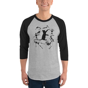 May include: A gray and black baseball tee shirt with a black cat silhouette surrounded by skeletons. The cat is jumping in the air and the skeletons are in various poses around it.