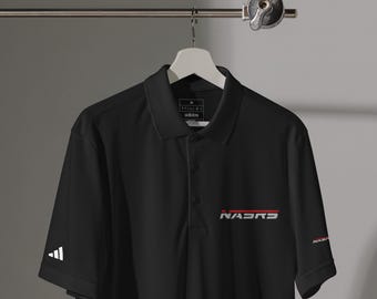 May include: Black polo shirt with a white Adidas logo on the left sleeve and the word "NASRS" in white and red on the chest. The shirt has a collared neckline and three buttons.