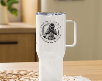 May include: White stainless steel travel mug with a black and white graphic of a race car driver wearing a helmet. The graphic is surrounded by a circle with the text "I've got some driving to do! North American Sim Racing Series".