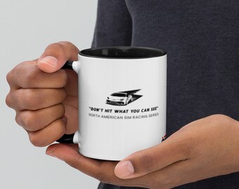 May include: A white ceramic mug with a black rim and handle. The mug features a black and white graphic of a race car with the text "Don't hit what you can see" and "North American Sim Racing Series".