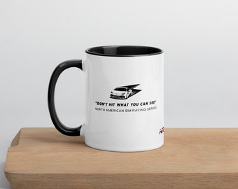 May include: White ceramic mug with a black rim and handle. The mug features a black and white illustration of a race car with the text "Don't hit what you can see" and "North American Sim Racing Series".