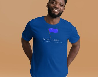 May include: Royal blue t-shirt with the text "RACING IS HARD..." and a blue flag graphic. The shirt also includes the text "NORTH AMERICAN SIM RACING SERIES" in a smaller font below the main text.