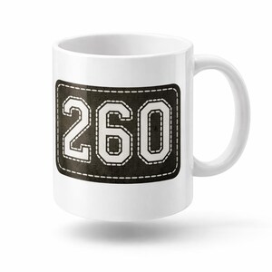 May include: White ceramic mug with a black and white stitched patch design. The patch features the number "260" in a bold, blocky font. The mug has a standard handle and a clean, minimalist aesthetic.