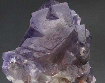 Fluorita cúbica púrpura (137 gramos), muestra de cristal maclado interpenetrante con zona fluorescente, Pakistán
