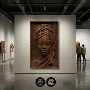 May include: A wooden relief sculpture of a woman with her eyes closed, wearing a head wrap, mounted in a rectangular frame. The artwork is displayed in a gallery setting, with two people in the background.