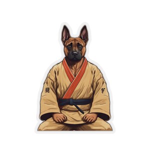 May include: A brown and black German Shepherd dog wearing a tan karate gi with a red sash and a black belt. The dog is sitting in a meditative pose with its paws crossed. The gi has the Japanese characters for "dog" and "study" on the sleeves.