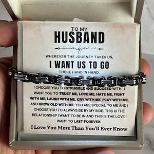 May include: A black and silver bracelet presented in a gift box. The card inside reads "TO MY HUSBAND" with a loving message. The bracelet is a chain link style, perfect for a special occasion.