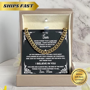 Puede incluir: Un collar de cadena de color dorado exhibido en una caja de regalo. El collar está colocado sobre una tarjeta con el texto "To My Son" y un mensaje sincero de "Love, Mom". La caja es de color beige y tiene un interior dorado.
