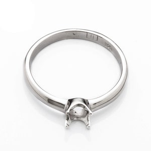 May include: A silver ring with a prong setting for a gemstone. The ring is marked with "925" on the inside band.