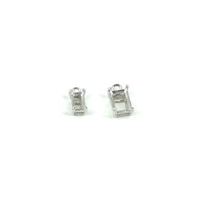 May include: Two small, rectangular silver jewelry settings with a loop at the top, designed to hold gemstones. The settings are empty, showcasing their open design and the potential for customization. The background is plain white.