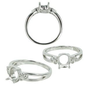 May include: Silver ring setting with a round oval shaped center stone and four small round stones on each side. The ring is made of sterling silver and has a polished finish.