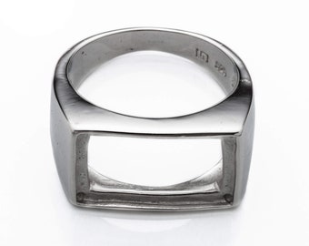 May include: A silver ring with a square-shaped cutout in the center. The ring is made of metal and has a polished finish.