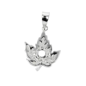 May include: Silver maple leaf pendant with a circular opening in the center. The pendant is designed to hold a gemstone or other embellishment.