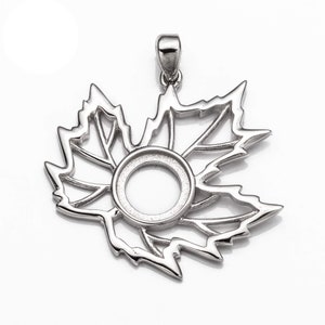 May include: Silver pendant in the shape of a maple leaf with a circular cutout in the center. The pendant has a bail at the top for attaching to a chain.