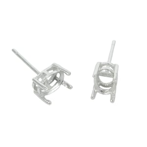 May include: Two silver earring settings with a prong setting for an oval shaped stone.