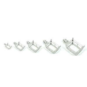 May include: Five silver-toned metal pendant settings for rectangular gemstones. The settings are of varying sizes, with the largest setting at the right and the smallest setting at the left.