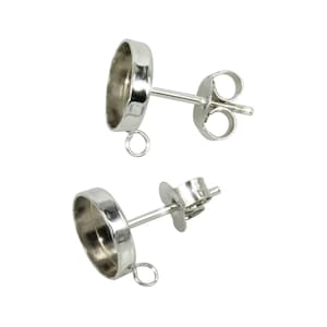May include: Two silver earring settings with a round bezel and a jump ring. The settings are designed to hold a cabochon stone.