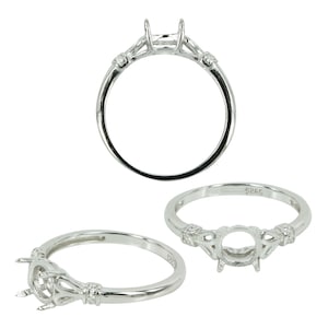 May include: A silver ring setting with a round center stone and two smaller stones on each side. The ring is made of sterling silver and is marked with the number 925.
