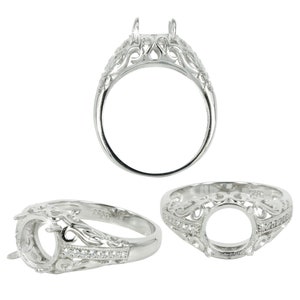 May include: Silver ring setting with a filigree design and a round center stone setting. The ring is accented with small clear stones.