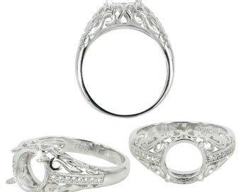 Puede incluir: Engaste de anillo de plata con un diseño de filigrana y un engaste de piedra redonda en el centro. El anillo está acentuado con pequeñas piedras transparentes.