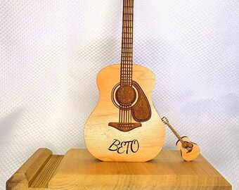 May include: A wooden guitar stand with a large and small wooden guitar. The large guitar has the name "Beto" engraved on it.