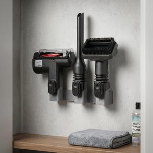 Puede incluir: Un juego de accesorios para aspiradora en negro y gris montado en la pared. El juego incluye un cabezal de cepillo motorizado, una boquilla para rincones y un cepillo para polvo, todo guardado en un soporte gris. Un paño de microfibra gris y una botella de solución de limpieza están sobre una superficie de madera.