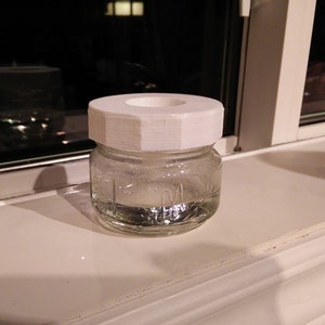 a glass jar with a white lid sitting on a window sill