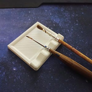 Op de afbeelding: Een set van drie keramische mokken met een gespikkelde, matte afwerking. De mokken zijn in crème, lichtgrijs en donkergrijs. Elke mok heeft een eenvoudig, minimalistisch ontwerp.