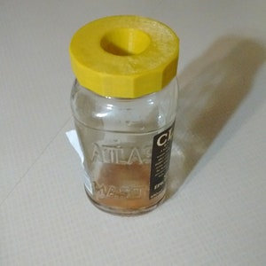 a glass jar with a yellow lid sitting on a table