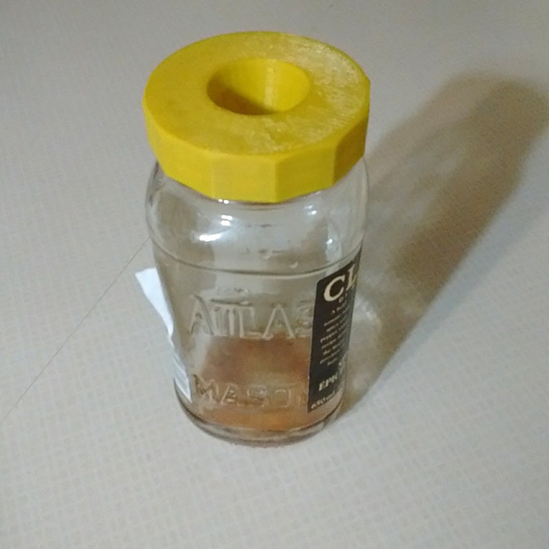 a glass jar with a yellow lid sitting on a table