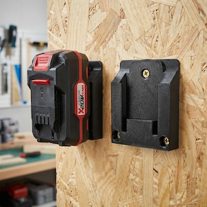 Può includere: Batteria nera e rossa per utensili elettrici con staffa di montaggio nera abbinata, entrambe fissate a una superficie in legno. La batteria riporta la scritta "X 20V TEAM". La staffa è progettata per contenere la batteria.