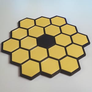 Può includere: Un design geometrico giallo e nero, simile a un favo o a uno specchio segmentato. Il design presenta molteplici forme esagonali gialle circondate da bordi neri, con un singolo esagono nero al centro.