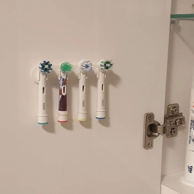 four toothbrushes hanging on a wall in a bathroom
