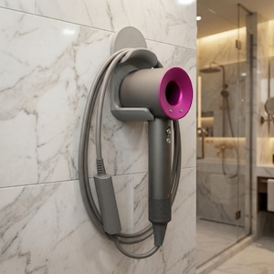 May include: A gray and magenta hair dryer mounted on a wall. The hair dryer is in a gray holder with the cord neatly wrapped around it. The wall is covered in white marble tiles.